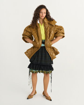 Model wearing a light brown jacket over a black midi skirt