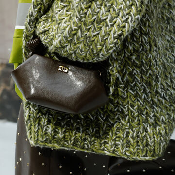 Close-up of a textured green tweed or bouclé garment paired with a dark leather bag