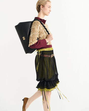 Model wearing a black skirt outfit with a black shoulder bag