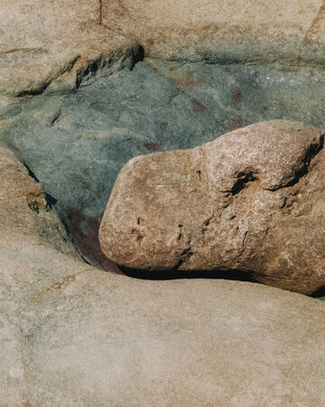 Close-up view of clear shallow water rippling gently over smooth, light-colored riverbed rocks