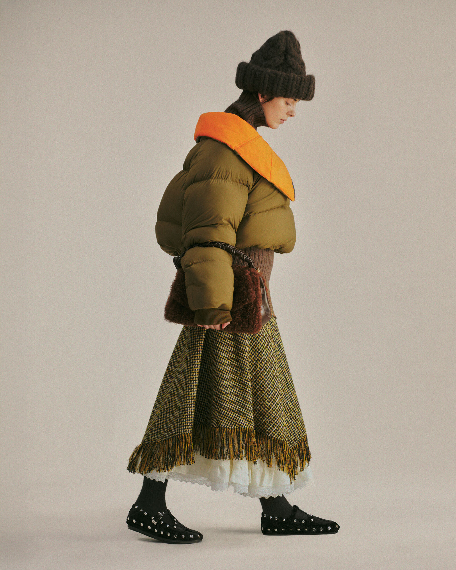 Olive GANNI puffer worn with a large brown knit hat and fringed skirt