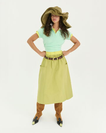 Model wearing a green skirt and green oversized hat