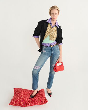 Model wearing a blue layer top, light blue jeans, and red shoes