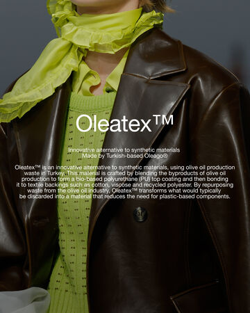 Front view of a person wearing a green knit and scarf with a brown coat featuring circular white text overlay reading Oleatex