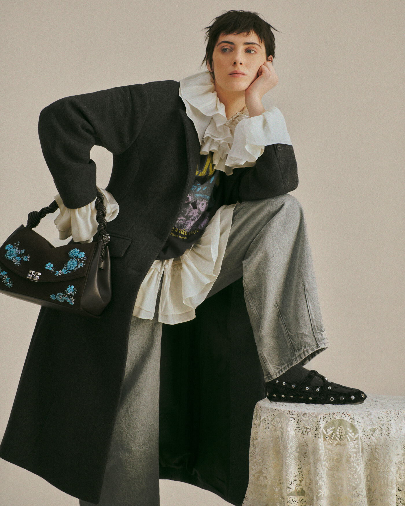 Grey GANNI coat layered over a graphic T-shirt and white ruffles