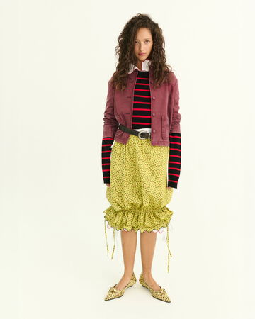 Model wearing a yellow ruffled skirt with a purple jacket