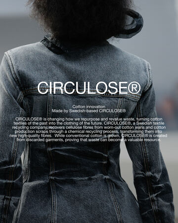 Back view of a person wearing a structured grey denim jacket featuring circular white text overlay reading CIRCULOSE