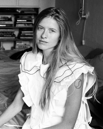 Black and white portrait of two models sitting on a bed wearing white GANNI ruffled shirts for the Spring Summer 2027 presentation