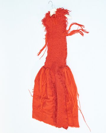 STEM material sample: Close-up of a vibrant orange loose-weave fringed textile sample hanging against a white background