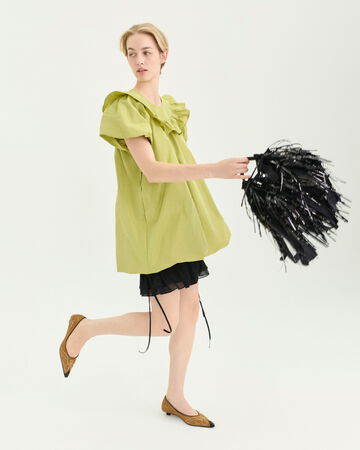 Model wearing a green mini dress and a black fringe handbag
