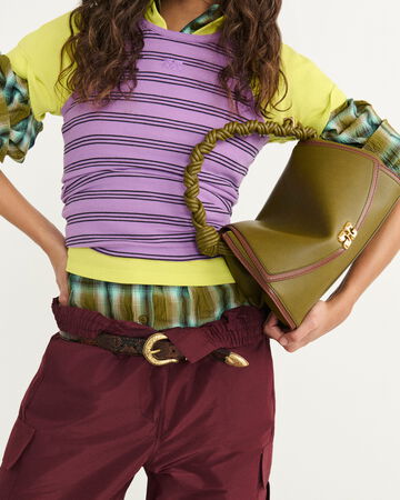 Close-up of model wearing a purple top over a checked layered shirt and red pants