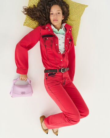 Model wearing a red jumpsuit and a purple handbag