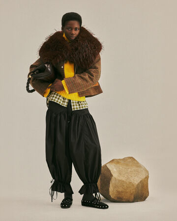 Model wearing a brown fur collar and black pants from the Fall/Winter 2026 collection