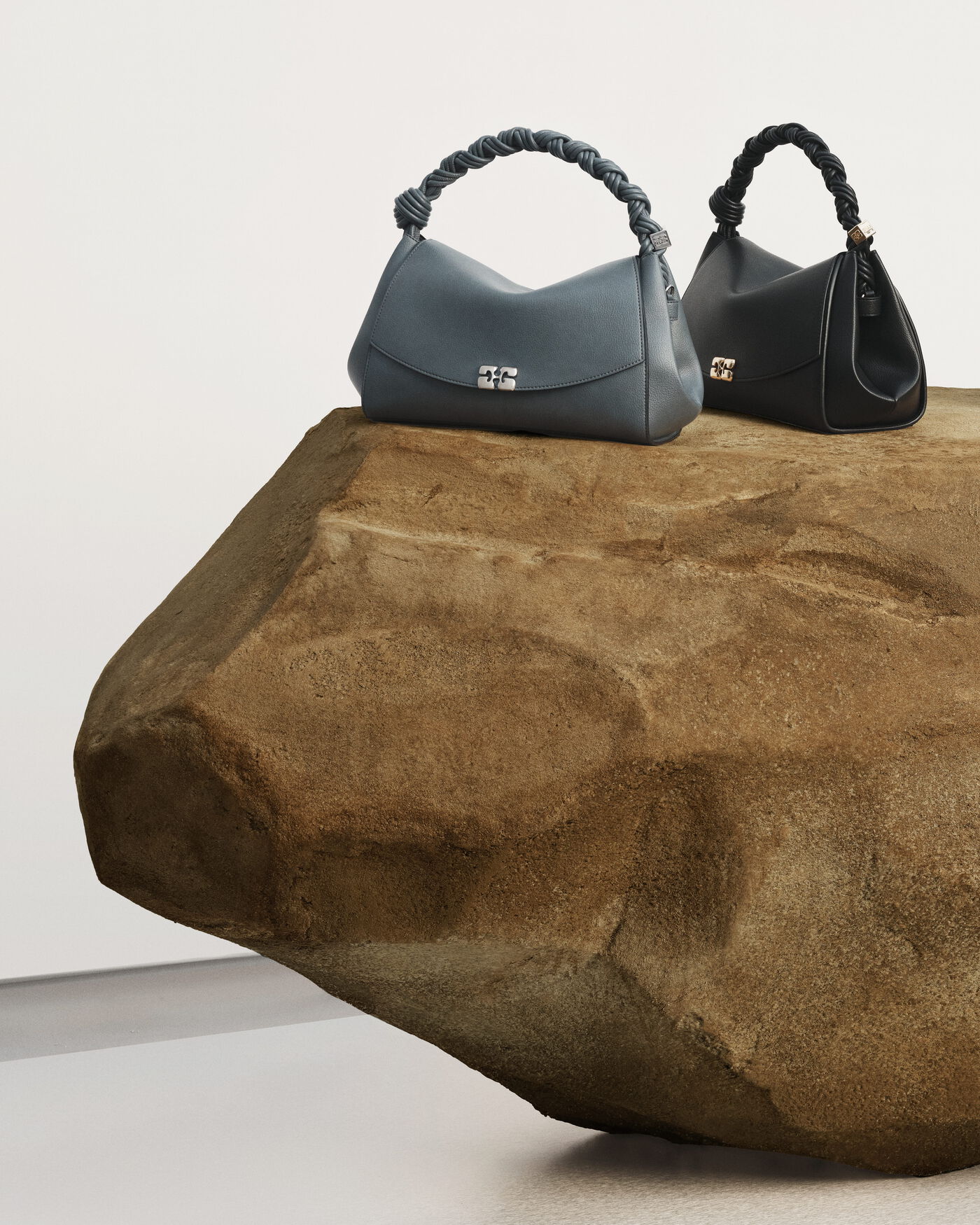 GANNI handbags arranged on a rough stone platform