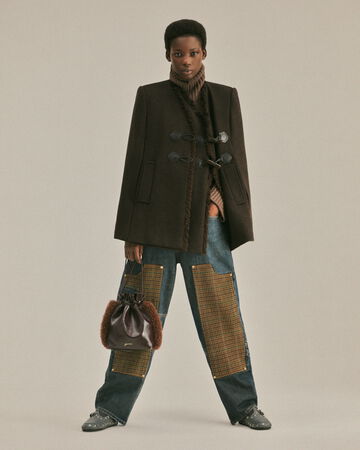 Model wearing brown jacket and checked jeans from the Fall/Winter 2026 collection