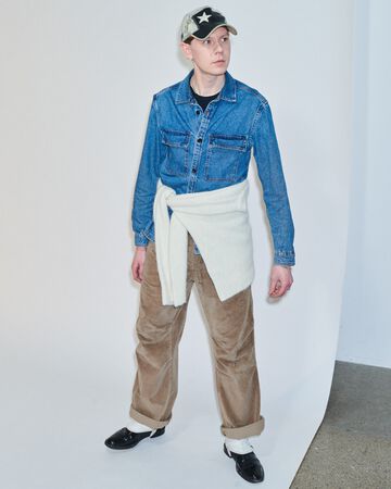 Future Talent Fabrics by Nicklas Skovgaard: Nicklas posing in a long-sleeve blue denim top with a wide cream-colored wrap skirt over tan trousers
