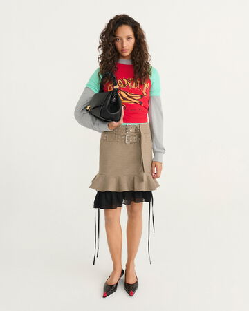 Model wearing a high-neck sleeveless top with a dark layered skirt