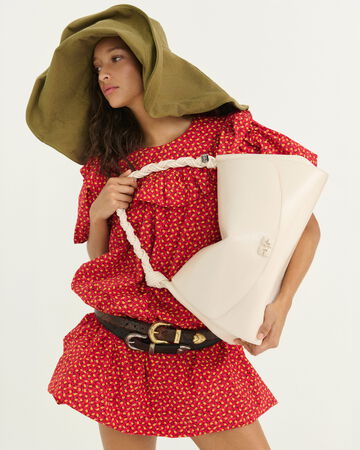 Model wearing a red dress and a green oversized hat